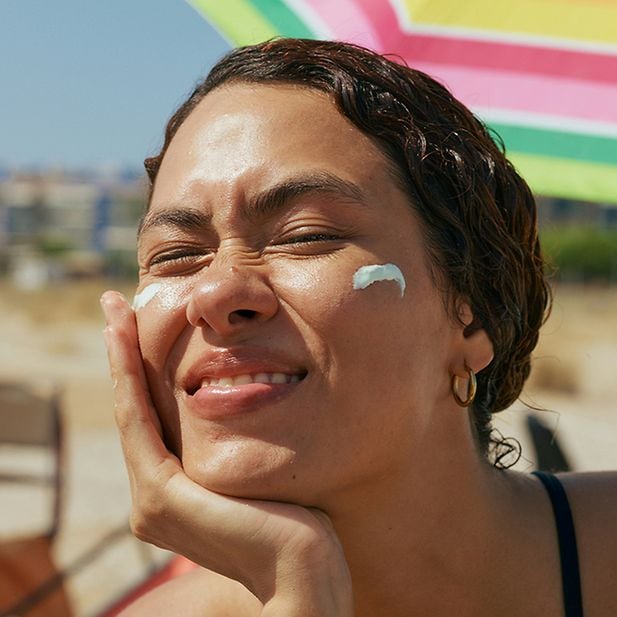 Woman applies sunscreen to her face
