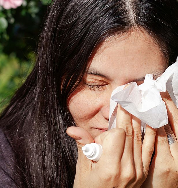 Woman dries eyes with tissue after applying eye drops