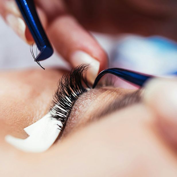 Eyelash technician attaching false eyelashes to an eye
