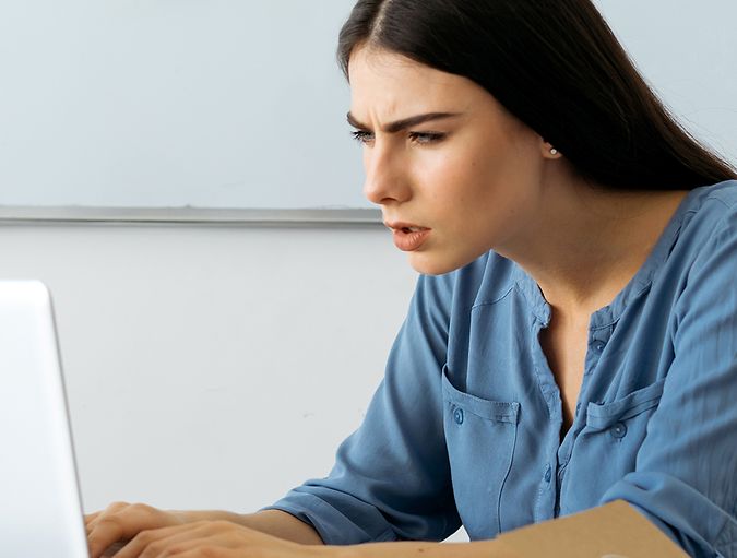Woman frowns and squints at her laptop