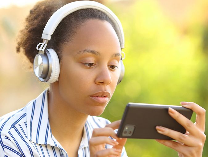 Woman wearing headphones watches a video on her phone