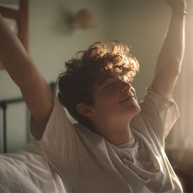 young boy wakes up and stretches, smiling
